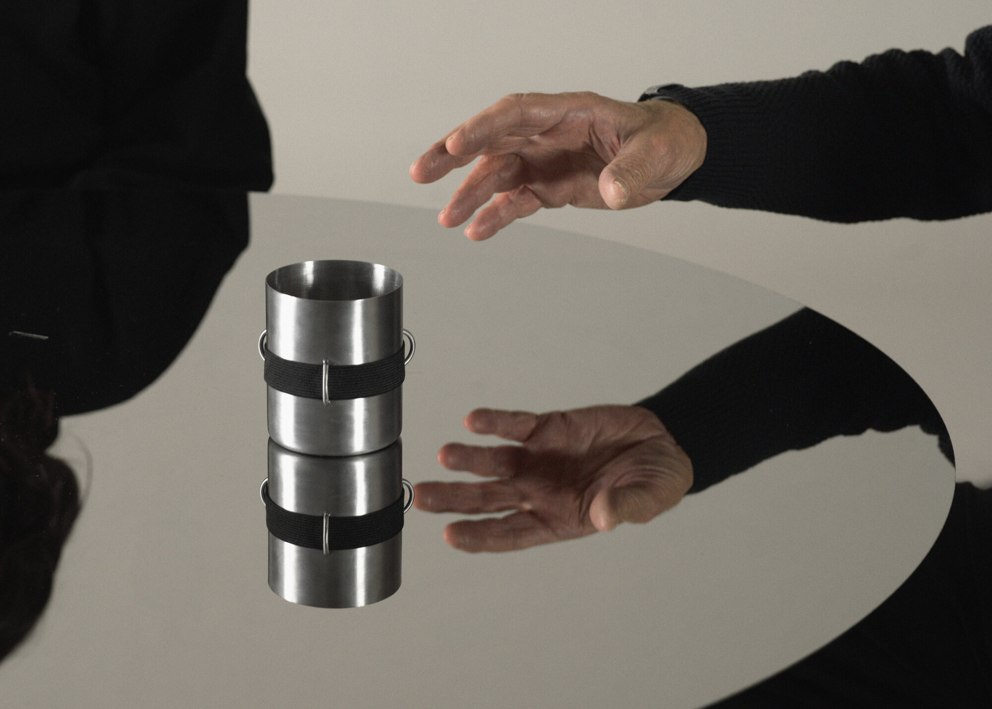 Tavola Distorta — object mid-air, hands releasing the cup
